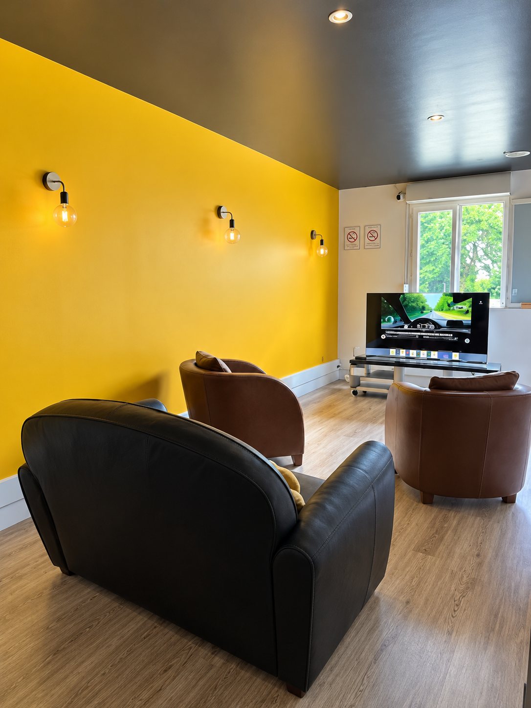 Salle de code avec mur jaune, fauteuils et écran